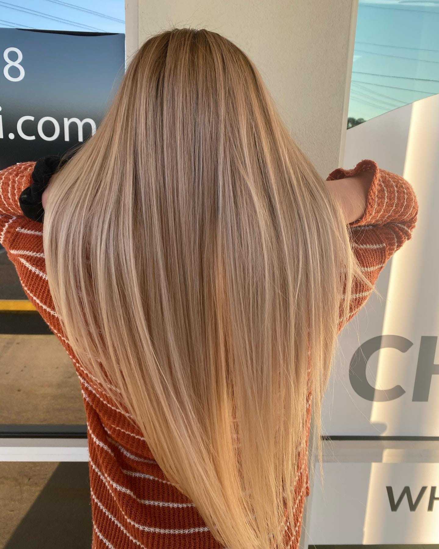 Long straight blonde hair, person facing away, wearing a striped sweater.